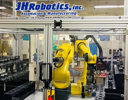 A yellow FANUC robot integrated into a JH Robotics machine tending work cell on the shop floor